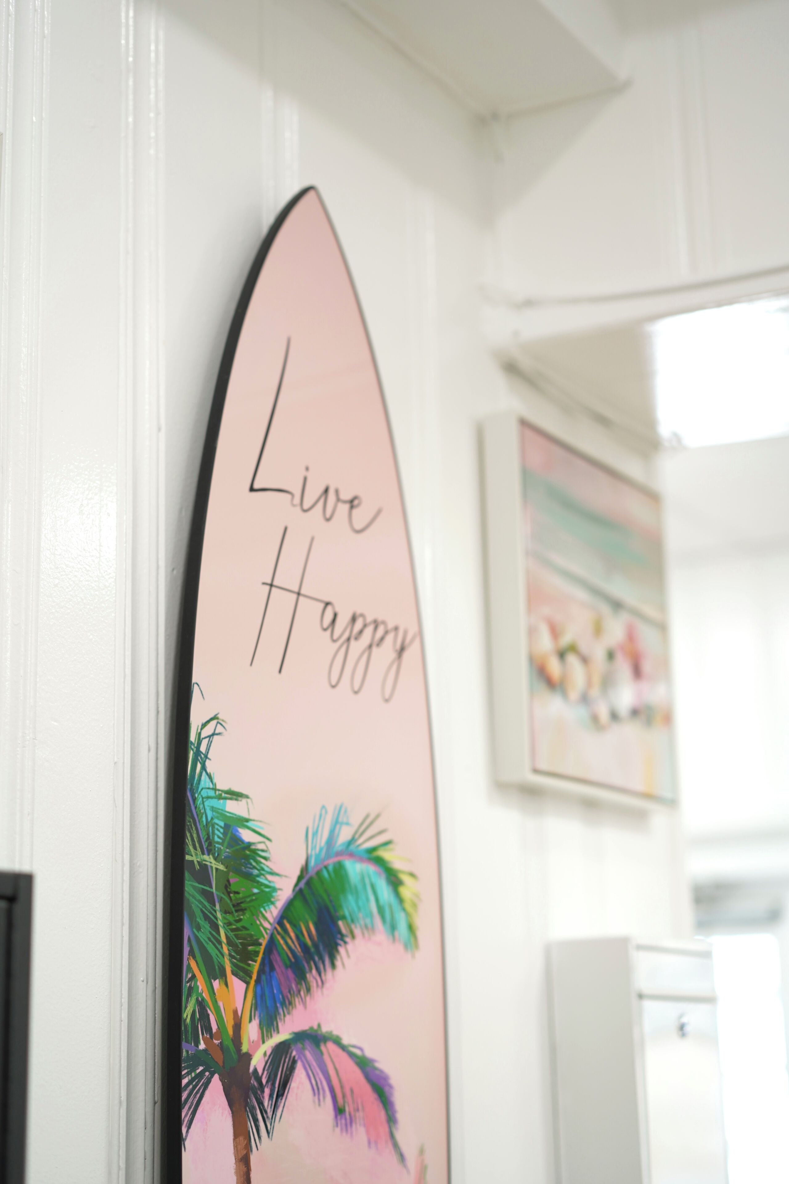 Una tabla de surf con la inscripción 'Live Happy' en una pared.