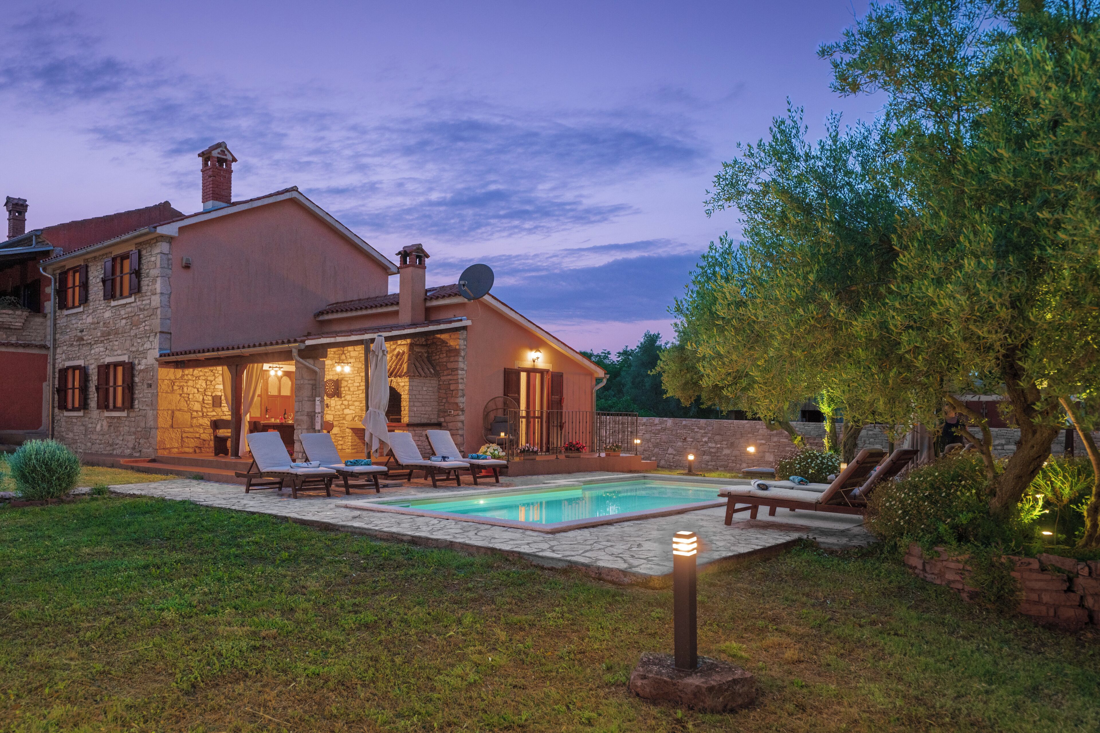 A two-story house with a swimming pool, outdoor seating, and a well-maintained garden.