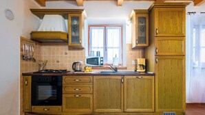 A kitchen with wooden cabinets, a stove, and a microwave. - Villa Natalie (Istria - Rakalj) (Rakalj)