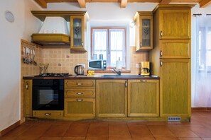 A kitchen with wooden cabinets, a stove, and a microwave. - Villa Natalie (Istria - Rakalj) (Rakalj)