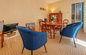 Ein Essbereich mit Holztisch, Stühlen, einem Fernseher und einer Topfpflanze.