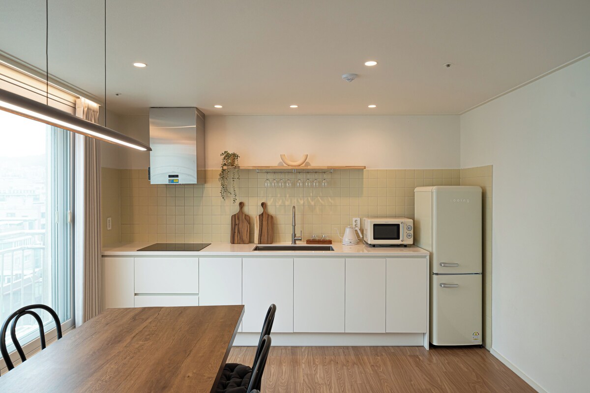 Una cocina moderna con una mesa de comedor, armarios blancos, un microondas y un refrigerador.