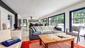 A spacious living area with a sofa, a wooden coffee table, and a dining area with chairs. - Luxueuse Villa avec piscine (Saint-Laurent-de-la-Pr)