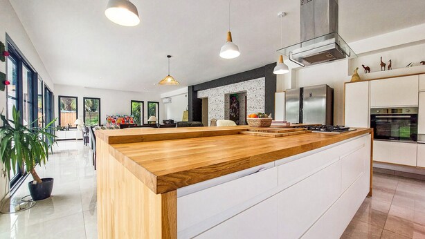 A modern kitchen with a wooden island, stainless steel appliances, and pendant lighting. - Luxueuse Villa avec piscine (Saint-Laurent-de-la-Pr)