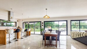A spacious kitchen with a dining area, large windows, and a modern chandelier. - Luxueuse Villa avec piscine (Saint-Laurent-de-la-Pr)
