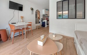 A compact living space with a kitchenette, a dining area with two chairs, a small round table, and a sofa. - Appartement proche plage (Royan)