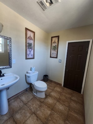 A bathroom with a sink, toilet, and two framed pictures on the wall.