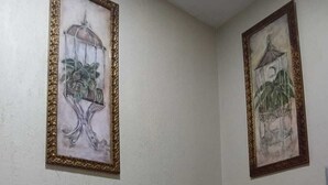 Un baño con un inodoro, dos obras de arte enmarcadas en las paredes y una toalla apilada sobre el inodoro.