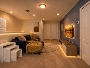 A cozy living room with a sofa, a coffee table, a TV, and a fireplace.
