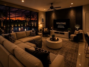 A modern living room with a large TV, comfortable seating, a pool view, and a 'WELCOME' sign. - Spacious 5-bedroom with private pool (Davenport)