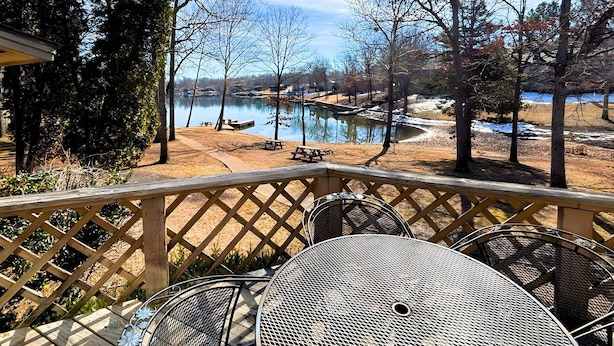 A deck with a view of a lake, picnic tables, and a metal table. - Los Indios sits on a secluded cove on Lake Thunderbird (Cherokee Village)