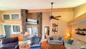 A living room with a stone wall, a ceiling fan, and a fireplace. - Los Indios sits on a secluded cove on Lake Thunderbird (Cherokee Village)