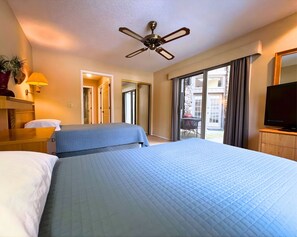 Ein Hotelzimmer mit zwei Betten, einem Deckenventilator, einem Fernseher und Blick ins Freie.
