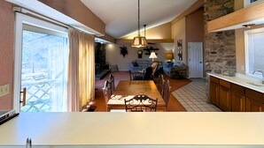 Un vaste espace de vie comprenant une salle à manger, une cuisine et un mur en pierre.