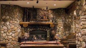A stone fireplace with a wooden mantel, a stone wall, and a wooden ceiling. - New Renovation. Comfort, Convenience, and Alpine Adventure in a Cozy Getaway (Crested Butte)
