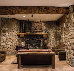 Una chimenea de piedra con repisa de madera, pared de piedra y techo de madera.