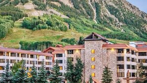 Ein Hotel mit mehreren Gebäuden, einem Berg im Hintergrund und umgebender Bepflanzung.