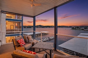 Ein Balkon mit Blick auf ein Gewässer und anlegende Boote, ausgestattet mit Ledersesseln und einem Tisch.
