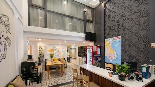 A hotel lobby with a dining area, a reception desk, and a large wall map.