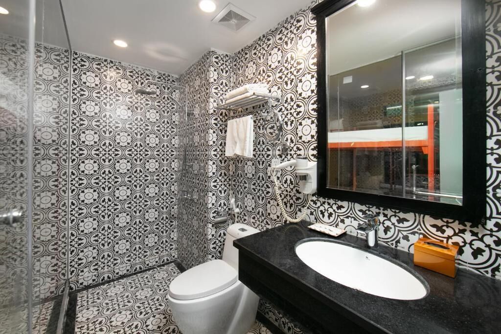 A bathroom with patterned tiles, a white toilet, a black sink, and a mirror.
