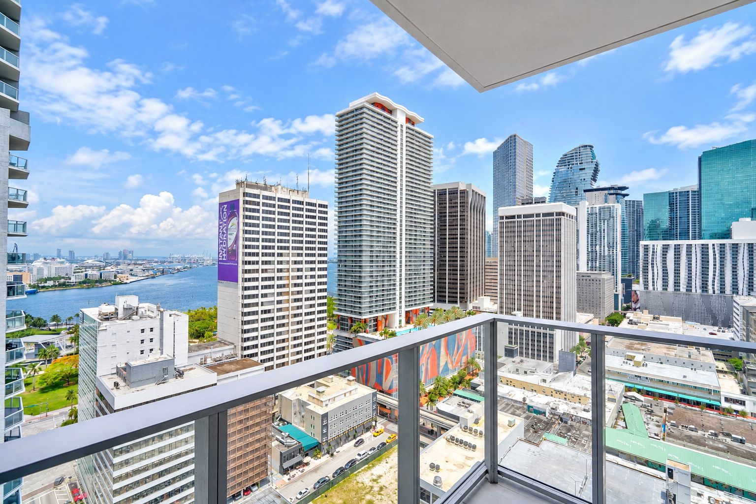 A high-rise building with a view of a cityscape, including other tall buildings and a river.