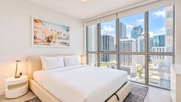 Una habitación de hotel moderna con una cama grande, vista a la ciudad y una obra de arte enmarcada en la pared.