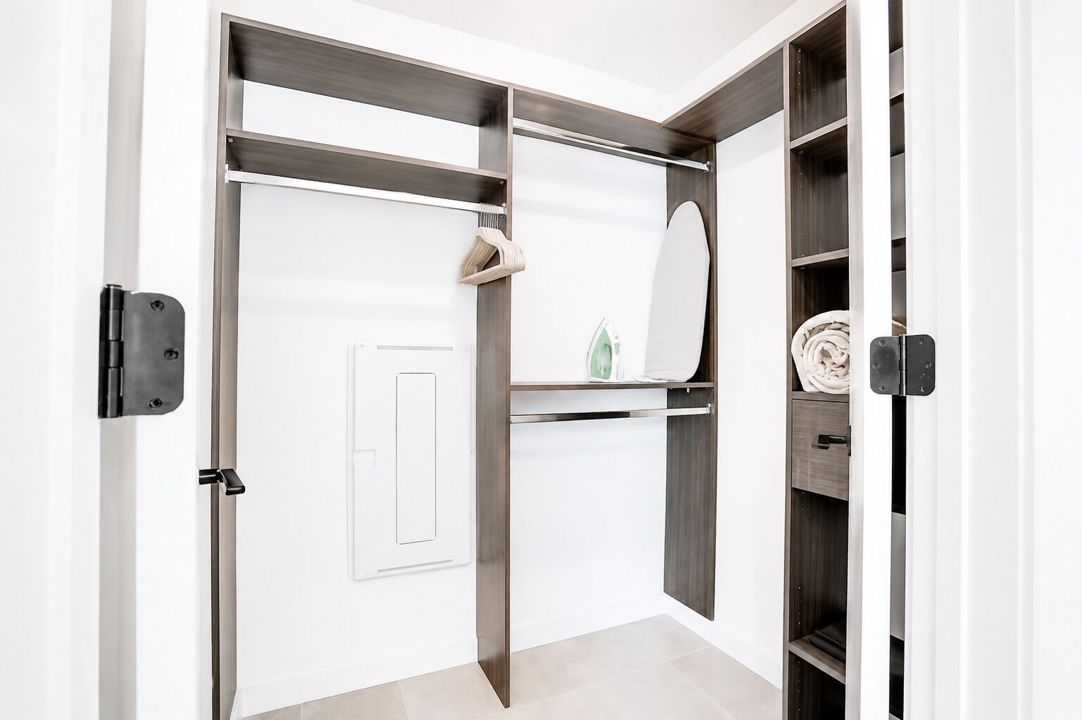 A walk-in closet with a mirrored section, shelves, and a door with a handle.