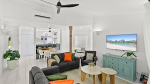 Ein modernes Wohnzimmer mit Sofa, Sesseln, Couchtisch und Fernseher.