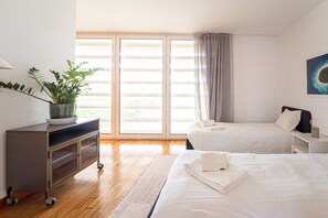 Ein Hotelzimmer mit Bett, Nachttisch, Pflanze und einem Fenster mit Vorhängen.
