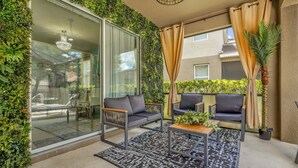 Ein Balkon mit Glastür, zwei Sofas, einem Couchtisch und einem gemusterten Teppich.
