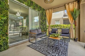 A balcony with a glass door, two sofas, a coffee table, and a patterned rug. - Solterra Resort:Movie,Game & Lazy River near Disney! (Davenport)