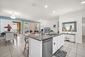 A modern kitchen with a central island, white cabinetry, and a large mirror above the sink. - Solterra Resort:Movie,Game & Lazy River near Disney! (Davenport)