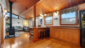 A spacious kitchen with wooden cabinets, a central island with stools, a built-in stove, and a refrigerator. - West Island Getaway - Unique 2 Bedroom Cottage (Fairhaven)