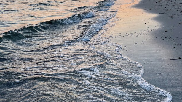 A beach with waves, a sunset, and a person walking. - West Island Getaway - Unique 2 Bedroom Cottage (Fairhaven)