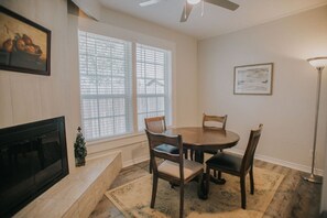 A dining area with a round table and four chairs, a fireplace, and two windows with blinds. - Executive Living 4BR 2BA in Beaumont (Beaumont)