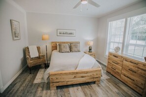 A bedroom with a wooden bed, a chair, a dresser, and a window with blinds. - Executive Living 4BR 2BA in Beaumont (Beaumont)