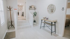 A hallway with a coat rack, a small table with a potted plant, and a wall-mounted decorative item. - Executive Living 4BR 2BA in Beaumont (Beaumont)