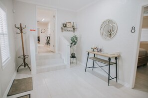 A hallway with a coat rack, a small table with a potted plant, and a wall-mounted decorative item. - Executive Living 4BR 2BA in Beaumont (Beaumont)
