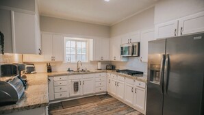 A modern kitchen with white cabinetry, stainless steel appliances, and a granite countertop. - Executive Living 4BR 2BA in Beaumont (Beaumont)