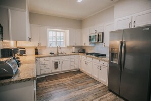 A modern kitchen with white cabinetry, stainless steel appliances, and a granite countertop. - Executive Living 4BR 2BA in Beaumont (Beaumont)