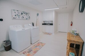 A laundry area with two washing machines, a sink, and a small cabinet. - Executive Living 4BR 2BA in Beaumont (Beaumont)