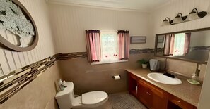Ein Badezimmer mit Toilette, Waschbecken, Spiegel und einem Fenster mit Vorhängen.