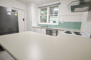 Eine Küche mit Kühlschrank, Geschirrspüler, Herd und Fenster mit Aussicht.