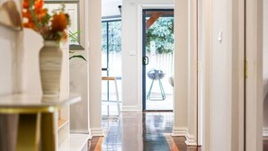 A hallway with a polished wooden floor, white walls, and a door leading to an outdoor area.