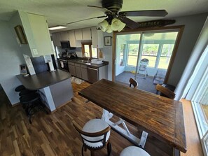 A modern kitchen with a central island, a dining table with chairs, and a ceiling fan.