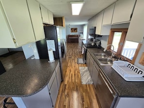 Una cocina compacta con encimeras de granito, electrodomésticos de acero inoxidable y una isla central.