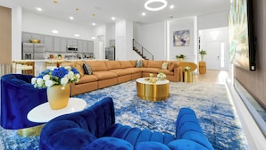 Un salon moderne avec un canapé d’angle, une table basse ronde et un tapis à motifs bleus.
