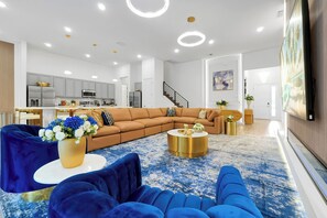 A modern living room with a sectional sofa, a round coffee table, and a blue patterned rug. - Luxury Resort Estate Near Disney, Convention Center,  ESPN Wide World of Sports (Orlando)
