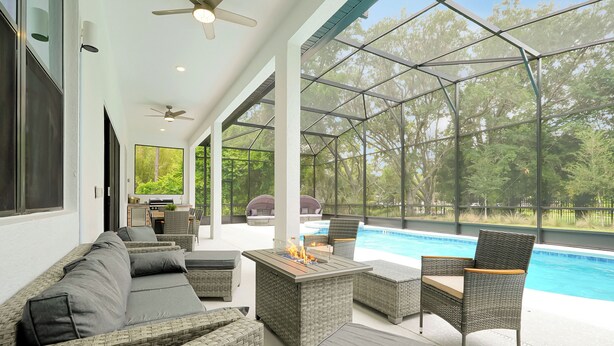 Un espace extérieur abrité comprenant une piscine, des meubles en osier et un foyer.