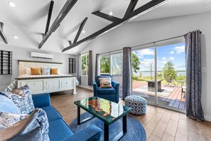 Ein modernes Schlafzimmer mit Bett, einer Couch, einem Couchtisch und Blick ins Freie.